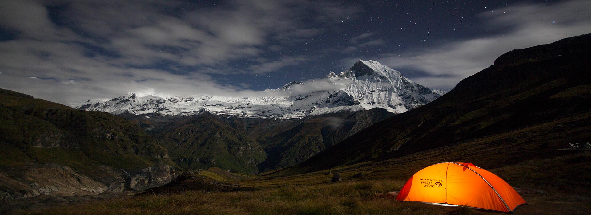 a lit tent and annapurna mountain range at night